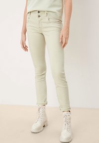 Ljusgröna skinny jeans i denim med en slät textur. Har en åtsittande design, framfickor och knappstängning. I kombination med vita kängor.