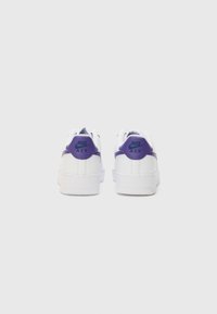 Nike Air-sneakers med överdel i vit läder, lila hälflik och kontrasterande turkos logotyp. Har en strukturerad vit gummisula.