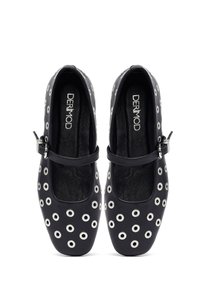 Scarpe in pelle nera con occhielli di metallo argentato a forma circolare e una tracolla stile Mary Jane. Suola piatta, punta arrotondata e rivestimento interno texture. Presentate dall'alto.
