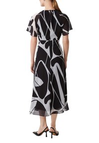 Czarna i biała abstrakcyjna sukienka w wzory z krótkimi, falbaniastymi rękawami, dopasowaną talią i zwiewnym dołem; posiada detal w postaci dekoltu w kształcie łezki z tyłu.