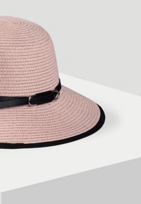 Różowy pleciony kapelusz słomkowy z solidną czarną wstążką i akcentem, szerokim rondem z kontrastowym czarnym wykończeniem, okrągły i strukturalny design.