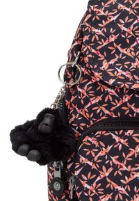 Svart tyg ryggsäck med mönster av rosa och orangea blad, utrustad med en lurvig svart gorilla nyckelring och fickor med dragkedja. Silverdetaljer.