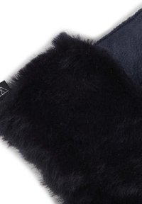 Tissu en velours noir avec une texture douce et floue d'un côté et un matériau sombre et lisse de l'autre, présentant une couture visible et une étiquette.