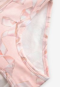 Tissu rose clair avec une finition satiné, comportant un motif de nœuds délicats. Encolure ronde avec des bords cousus et une texture lisse.
