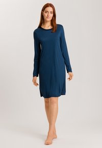 Vestido de manga larga azul marino hecho de una tela suave y lisa, con un escote redondo y un corte relajado, a la altura de la rodilla y con aberturas laterales.