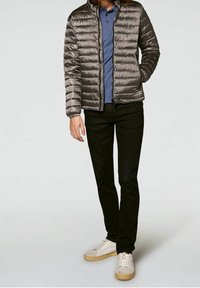 Gray puffer jacket with quilted design, blue polo shirt, black trousers, and white sneakers with beige soles. Casual, modern outfit presentation.