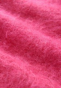 Material texturat de culoare roz, cu un aspect moale și pufoș, având fibre fine și delicat pe care creează un model de suprafață cald și primitor.