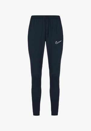 Tmavě modré tepláky Nike s elastickým pasem, designem zužujícím se dolů a bílým logem na levém stehně. Hladká textury látky.