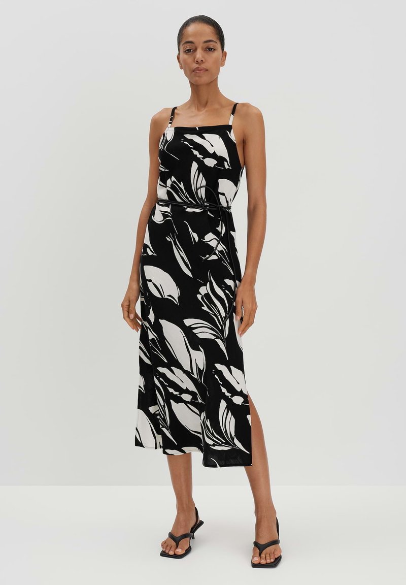 Schwarz-weißer Blumenmuster-Midi-Kleid mit dünnen Trägern und taillierter Taille, das einen seitlichen Schlitz für mehr Bewegungsfreiheit aufweist.