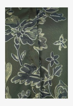 Grøn stof med et blomsterdesign i mørke og lyse nuancer, med en glat tekstur og konturerede detaljer, der fremhæver designet.