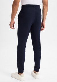 Marineblaue Sweatpants mit schmalem Schnitt, elastischem Bund und seitlichen Taschen. Hergestellt aus weichem Material mit Rippstrickbündchen an den Knöcheln.
