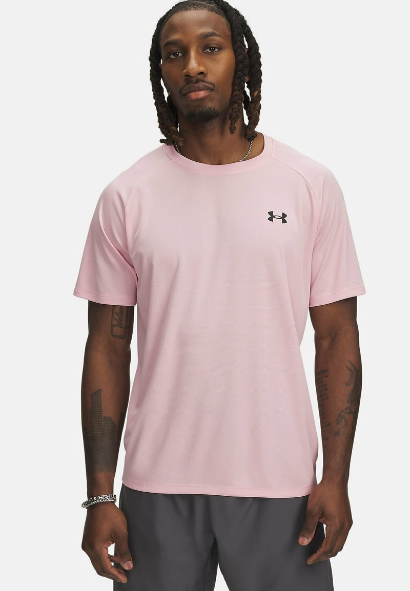 Světle růžové sportovní tričko s krátkým rukávem a kulatým výstřihem, vyrobené z texturované látky, s černým logem Under Armour na hrudi.