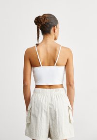 Biały ribbed crop top z cienkimi ramiączkami, w połączeniu z jasnobeżowymi spodniami cargo z bocznymi kieszeniami i elastyczną talią.