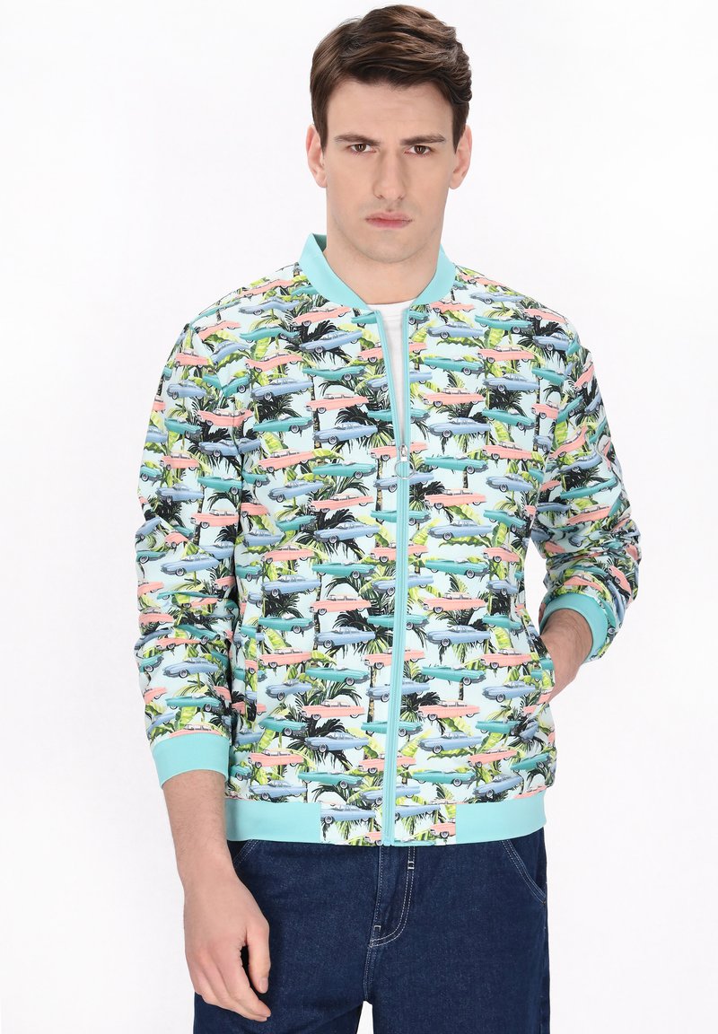 Giacca bomber colorata con stampa tropicale che presenta automobili e palme, realizzata in materiale leggero con chiusura a zip e polsini a coste.