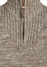 Maglione lavorato a maglia con colletto alto, dotato di chiusura a mezza zip. Il materiale è una miscela testurizzata di colori marrone e crema.