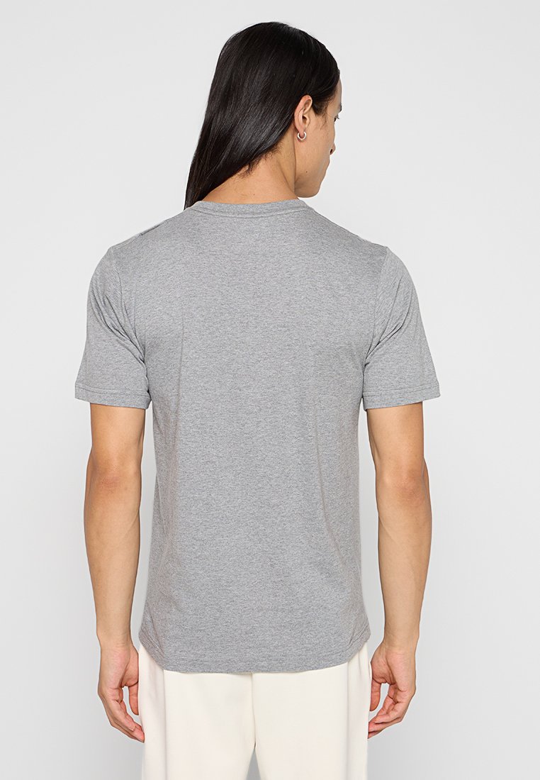 Camiseta de algodón gris con mangas cortas, cuello redondo y corte regular. Textura suave sin logotipos ni patrones visibles.