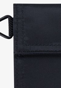 Schwarze Nylon-Tasche mit strukturierter Oberfläche, verfügt über eine Frontklappe und verstärkte Nähte. Enthält eine Metallschlaufe zur Befestigung an der Seite.