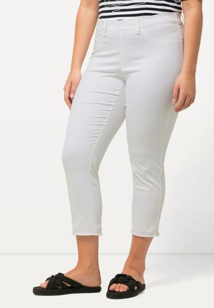 Jeans blancos cortos con una textura suave y un ligero estiramiento. Cintura de altura media, bolsillos delanteros y dobladillo deshilachado. Combinados con sandalias negras anudadas.