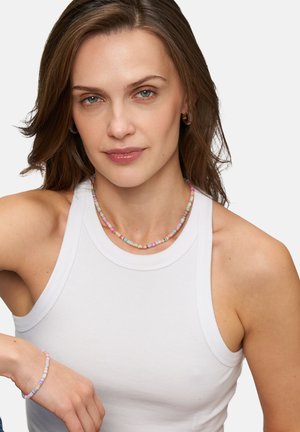 Kleurrijke kralenketting in pastelkleuren van roze, blauw en geel. Model draagt een strakke witte tanktop, waarmee de sieraden duidelijk zichtbaar zijn.