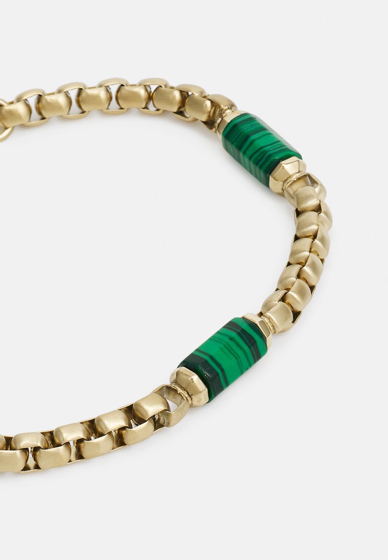 Bracelet en chaîne dorée mettant en avant des perles d'accent en malachite verte avec des rayures noires. Texture lisse avec une finition polie et des maillons métalliques.