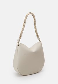 Bolso de hombro beige fabricado en piel suave con forma redondeada. Presenta un asa de cadena trenzada y un pequeño bolsillo frontal. Detalles en dorado.