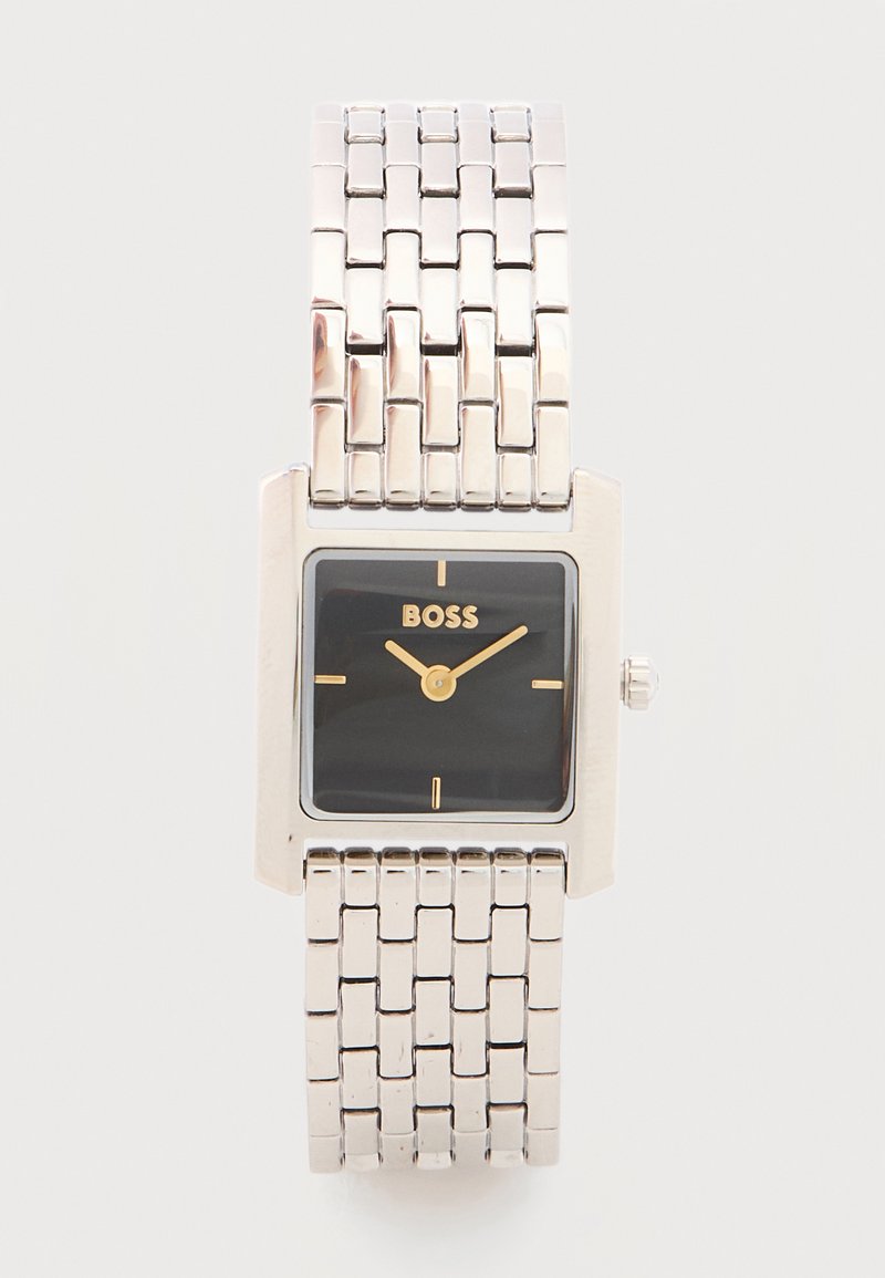 Ασημένιο μεταλλικό ρολόι με σύνδεσμο-βραχιόλι, τετράγωνο μαύρο καντράν, χρυστά δείκτες, χρυστοί δείκτες ώρας και το λογότυπο "BOSS" στη θέση 12 της ώρας.