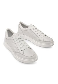 Białe skórzane sneakersy z perforowanymi bokami, płaskimi sznurówkami i wyściółką w podeszwie. Posiadają zaokrąglony czubek i kontrastowe detale w przeszyciach.