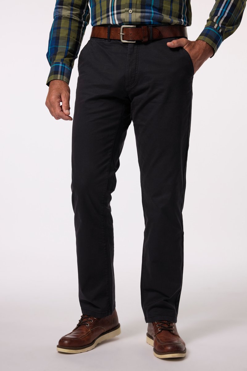 Mann trägt schwarze, gerade geschnittene Hose, braunen Ledergürtel, braune Lederschuhe und ein grün-blau kariertes Hemd mit langen Ärmeln.