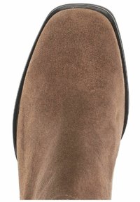 Bottine en daim marron à bout arrondi, semelle extérieure noire lisse et coutures minimales. Semelle légèrement incurvée pour un profil élégant.