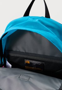 Ανοιχτό μπλε σακίδιο πλάτης που δείχνει την γκρι εσωτερική τσέπη με μια μαύρη ετικέτα που φέρει το λογότυπο και το κείμενο της μάρκας The North Face.