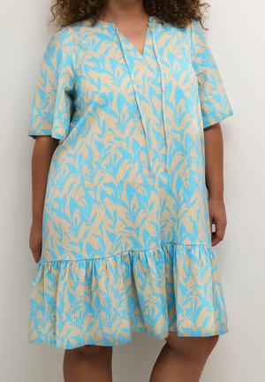 Kjole med korte ærmer i lysebeige med et blåt bladmønster, med V-hals, afslappet pasform og en flæse-hemline.