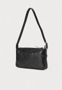 Borsa nera in pelle con superficie texture, cinturino sottile e regolabile, e chiusura con zip. Presenta un sottile design a onda nella parte superiore.