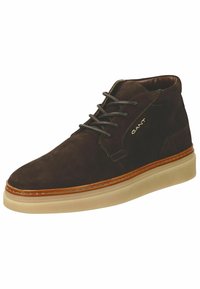 Braune Wildleder-Stiefelette mit gedämpften Schnürsenkeln, ausgestattet mit einer beigen Gummisohle und einer kontrastierenden braunen Ledermittelsohle. "GANT"-Logo an der Seite angebracht.
