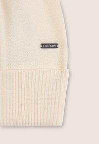 Beanie color crema con una texture a coste e un'etichetta logo piatta in argento con la scritta "FREDDY" sul lato. Materiale in maglia morbida.