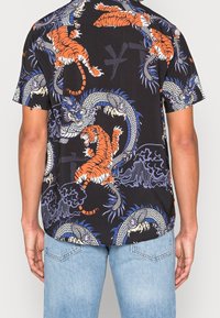 Koszula z krótkim rękawem z czarnym tłem, misternym nadrukiem tygrysa i smoka w kolorach pomarańczowym, niebieskim i białym, o luźnym kroju.