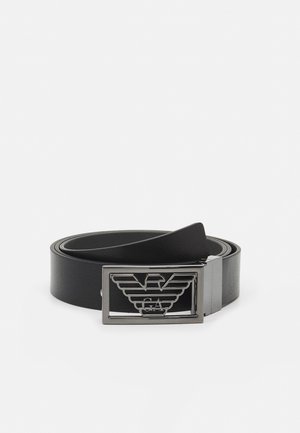 Cintura in pelle nera con una texture liscia e una fibbia in metallo argentato che presenta un design ad aquila e lettere incise "GA."