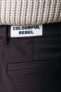 Pantalones de estampado de espiga marrón con un bolsillo trasero y una etiqueta de marca blanca que dice "COLOURFUL REBEL."