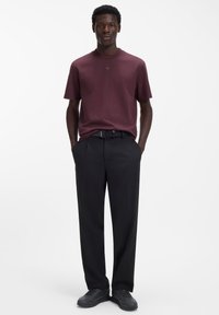 Bordeauxrotes T-Shirt mit kurzen Ärmeln und rundem Halsausschnitt, kombiniert mit schwarzen, maßgeschneiderten Hosen und abgerundet mit schwarzen Schuhen. Einfaches, elegantes Design.