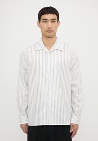 Camisa blanca de manga larga con rayas verticales negras, diseño con cuello, frontal abotonado y puños con acentos a rayas.
