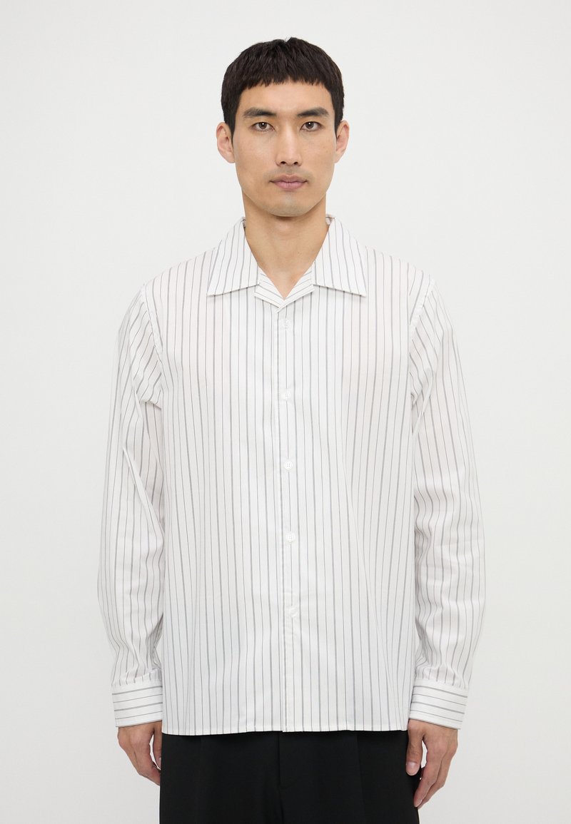 Camisa blanca de manga larga con rayas verticales negras, diseño con cuello, frontal abotonado y puños con acentos a rayas.