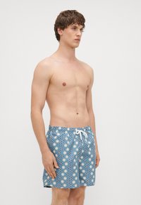 Vīriešu peldbikses zilā krāsā ar saules un punktu rakstu, ar elastīgu jostasvietu un baltu auklu, izgatavotas no viegla auduma.