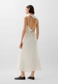 Helles, ärmelloses Kleid mit tiefem, offenem Rücken, tailliertem Bund und Bindegürtel im Rücken. Glattes, strukturiertes Material mit einem fließenden Design.