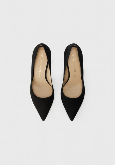 Black suede high heels with a pointed toe, smooth texture, and a low-cut design exposing the foot. Gold brand name inside.