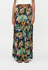 Jupe maxi avec un motif de feuilles tropicales vibrantes multicolores, tissu léger, devant boutonné, sur un fond noir.