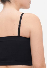 Fekete, varrás nélküli bralette állítható pántokkal és széles pánttal. Puha, rugalmas anyagból készült, letisztult, minimalista dizájnnal.
