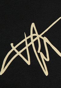 Tessuto nero con un evidente disegno astratto dorato a firma. La texture è liscia, con dettagli fini nelle cuciture.