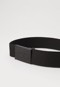 Black woven belt made of durable fabric, featuring a rectangular black metal buckle with embossed branding on the front.