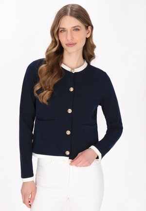 Navy blue cardigan with long sleeves, round neckline, and gold buttons. Features two front pockets and white accents at the collar and cuffs.
