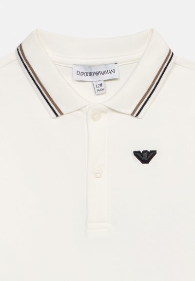 Λευκό παιδικό πόλο μπλουζάκι με καφέ και μαύρο ριγέ γιακά, δύο κουμπιά, ετικέτα Emporio Armani και μαύρο κεντημένο λογότυπο στο στήθος.