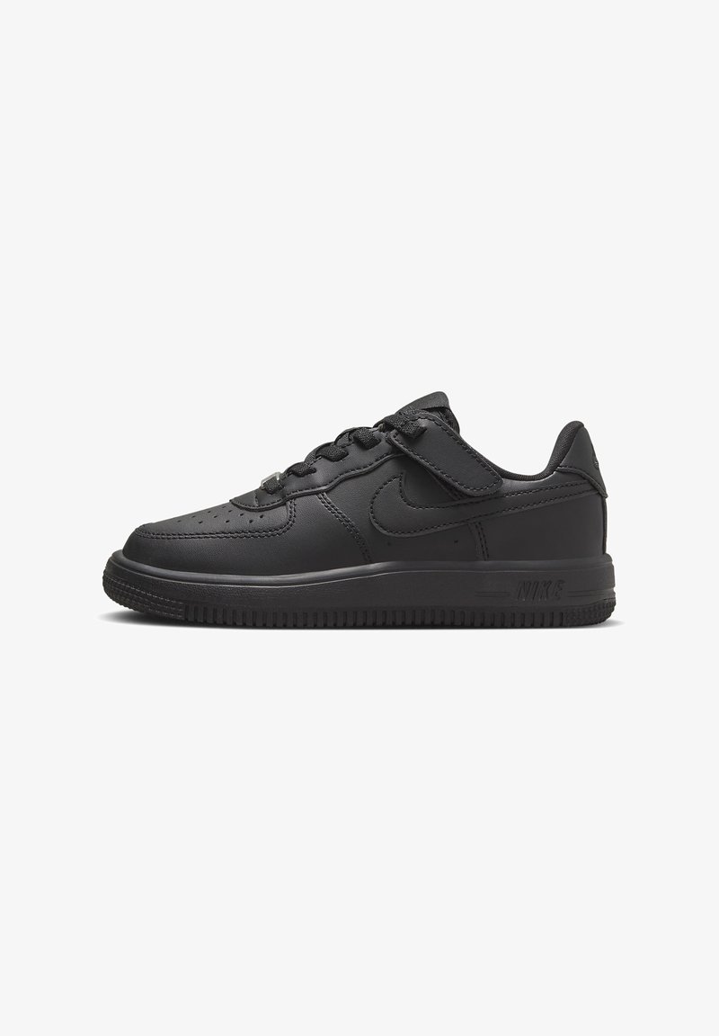 Baskets basses noires Nike avec lacets, une bande Velcro, embout perforé et semelle texturée sur fond blanc.